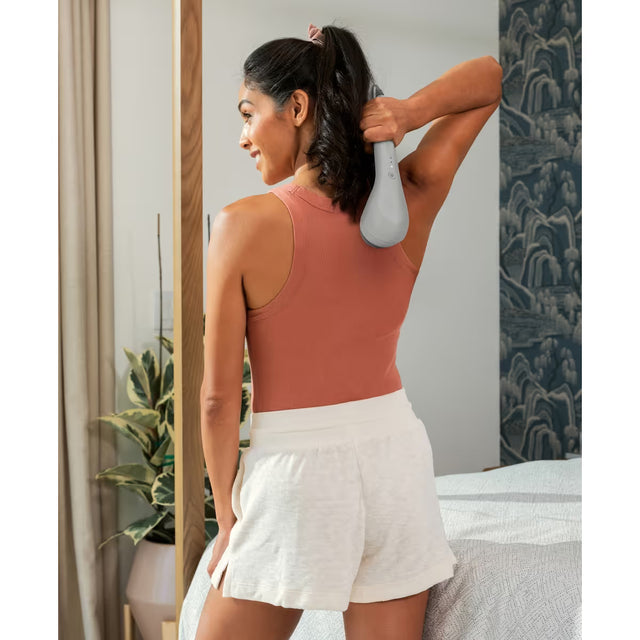 Woman using a handheld massager in a bathroom setting - okotoks hc pharmacy