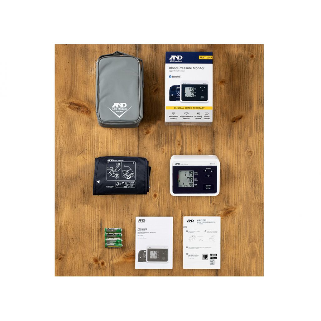 Blood pressure monitor set with case, batteries, and packaging on a wooden surface - Okotoks HC Pharmacy