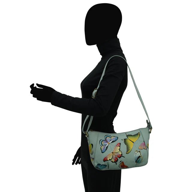 Silhouette of a person holding a light blue handbag with butterfly designs on a white background - okotoks hc pharmacy