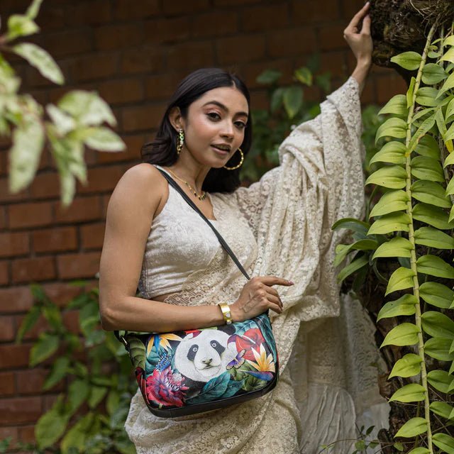 Woman holding a colorful bag with a panda design, standing in front of a brick wall and green plants. - okotoks hc pharmacy