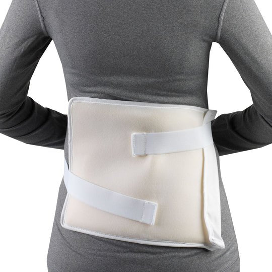 A back support brace with white straps and a beige foam insert, shown worn on a person's lower back against a white background. - okotoks hc pharmacy