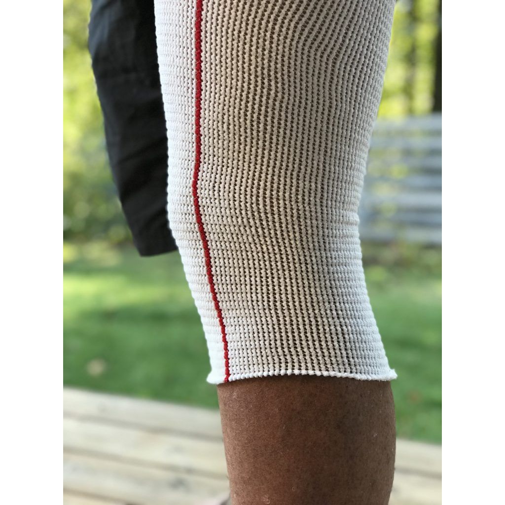 Close-up of a person wearing a white sleeve with a red stripe on a blurred outdoor background - okotoks hc pharmacy