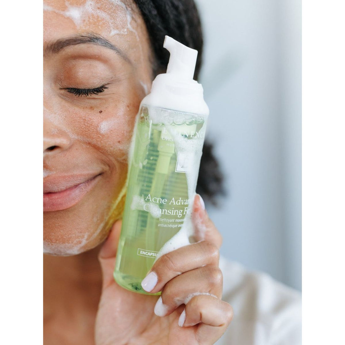 Person holding a bottle of Acne Advance Cleansing Gel with a blurred background - okotoks hc pharmacy