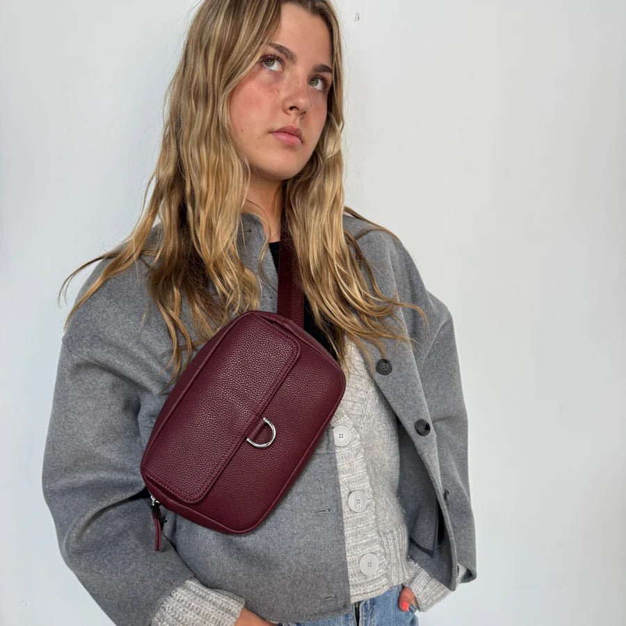 Woman wearing a gray coat with a maroon crossbody bag against a white background - okotoks hc pharmacy