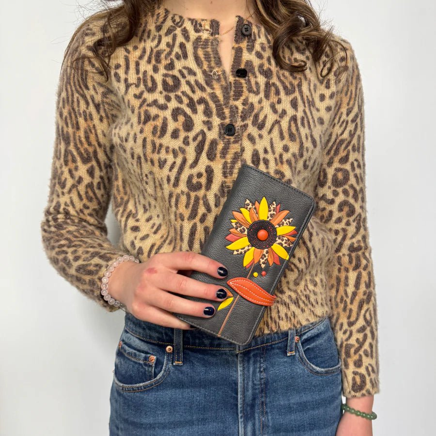 Person wearing a leopard print shirt holding a grey wallet with floral designs. - okotoks hc pharmacy