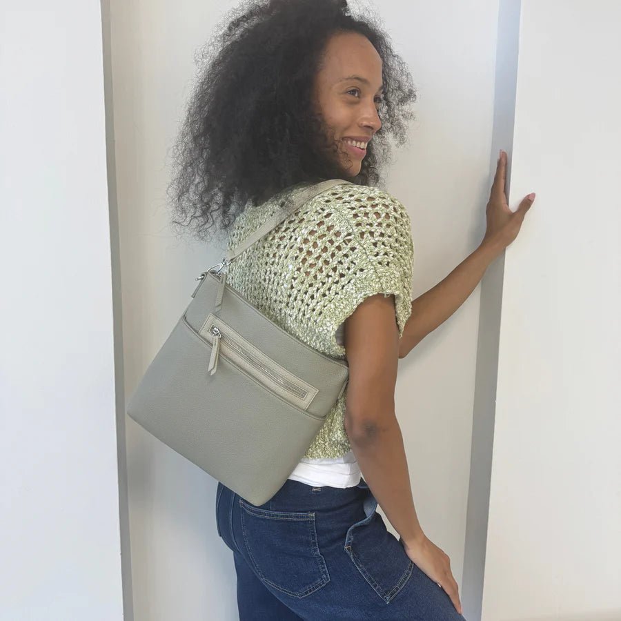 Woman holding a gray handbag against a plain background - okotoks hc pharmacy