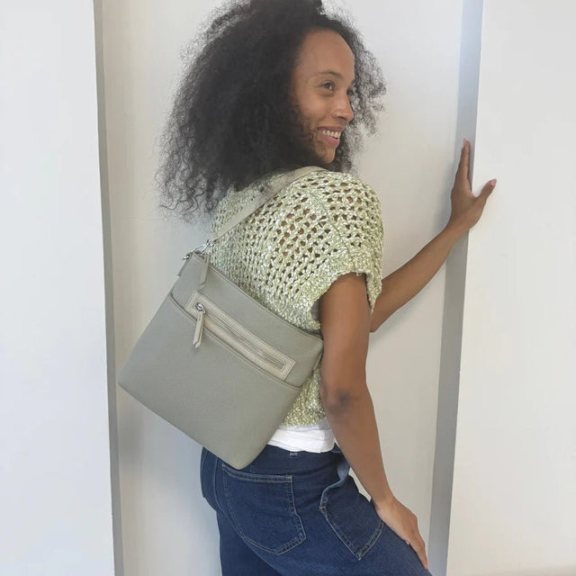 Woman holding a gray handbag against a plain background - okotoks hc pharmacy