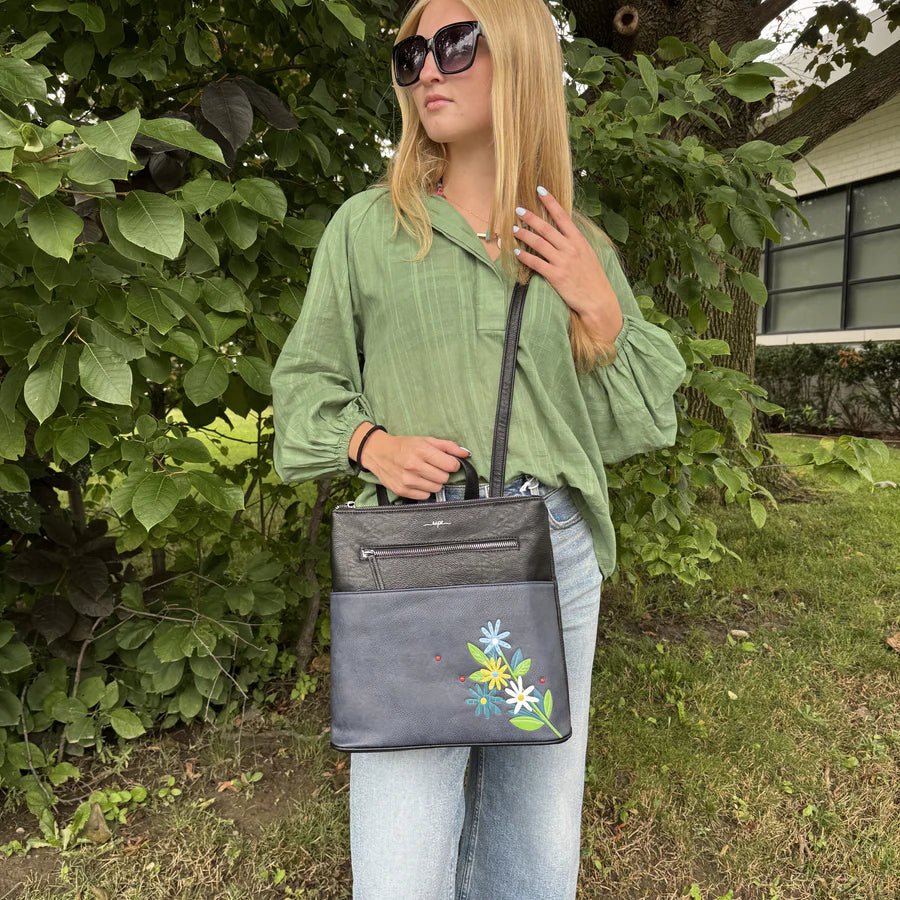 Woman holding a black handbag with floral designs outdoors - okotoks hc pharmacy