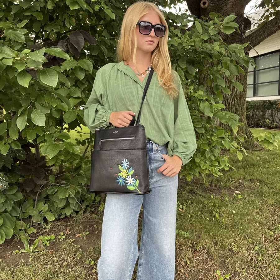 Person holding a black handbag with floral design outdoors - okotoks hc pharmacy