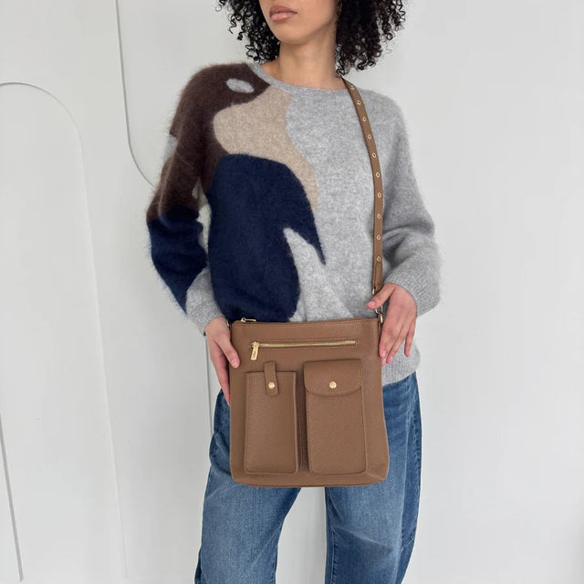 Woman holding a brown handbag against a white background - okotoks hc pharmacy