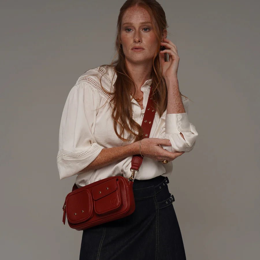 Woman holding a red handbag against a plain background - okotoks hc pharmacy