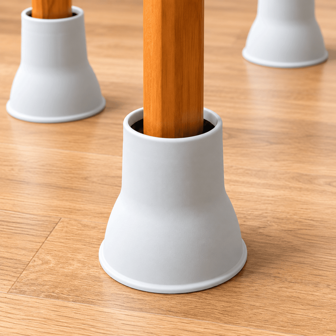 White bell-shaped table leg protectors on a light wood floor, with wooden table legs inserted in the center. - okotoks hc pharmacy
