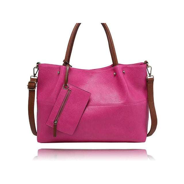 A bright pink pebbled leather tote bag with brown leather handles, a detachable shoulder strap, and a matching zippered pouch, shown on a white background with a reflection. - okotoks hc pharmacy