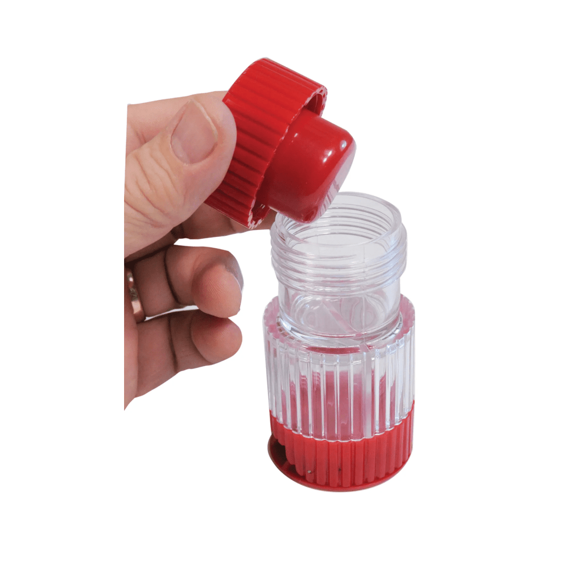 Hand holding a small red and clear plastic container with a red cap on a white background - okotoks hc pharmacy