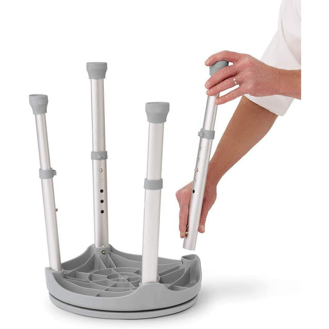 Gray adjustable stand with multiple legs being adjusted by a person's hand on a white background - okotoks hc pharmacy