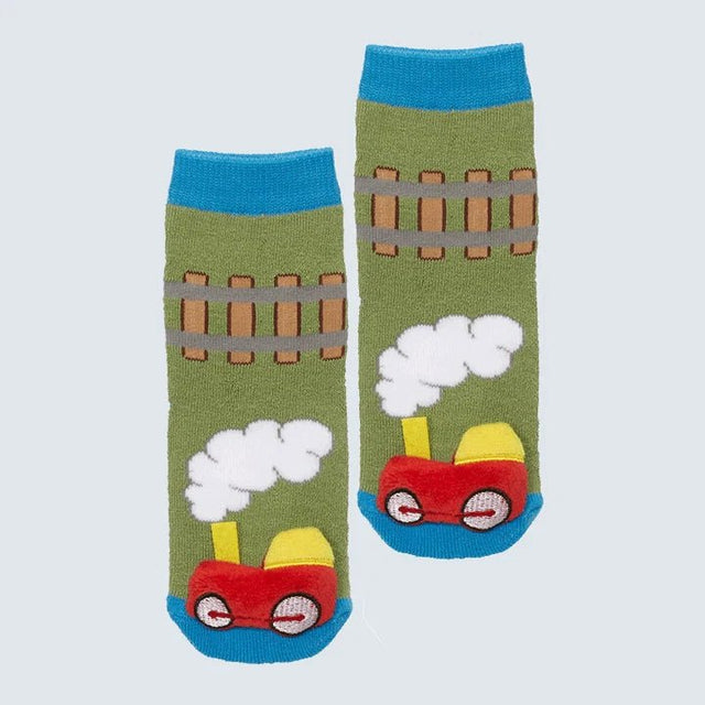 A pair of green crew socks featuring a cartoon train design with a red engine, yellow details, white steam clouds, and brown fence stripes, set against a light gray background. - okotoks hc pharmacy