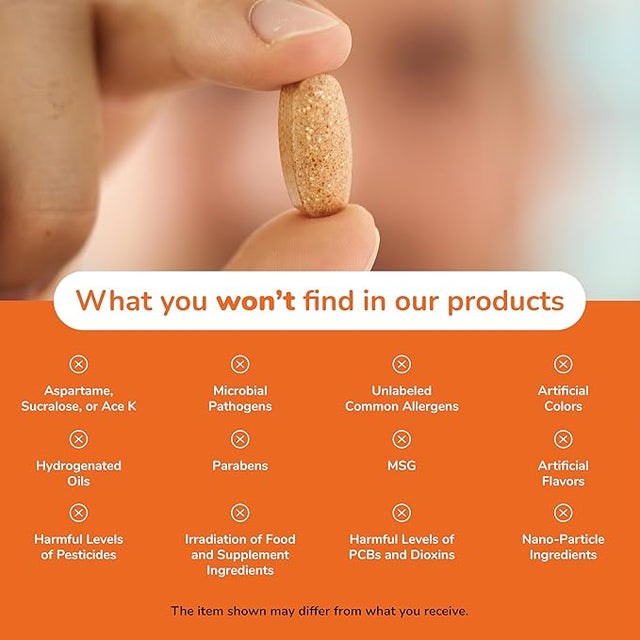 Hand holding a pill with a list of ingredients not found in their products on an orange background - okotoks hc pharmacy