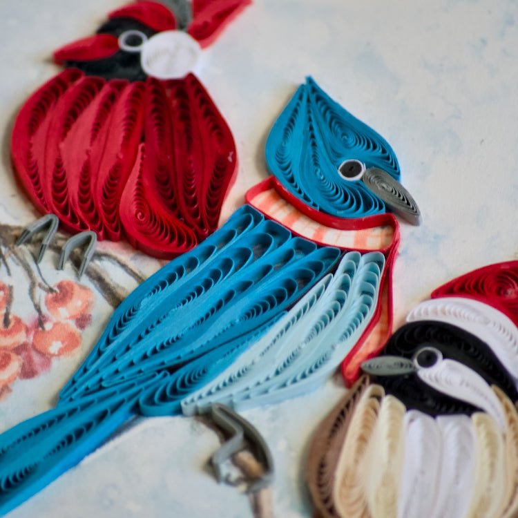 Quilled paper birds in red, blue, and beige on a textured surface - okotoks hc pharmacy