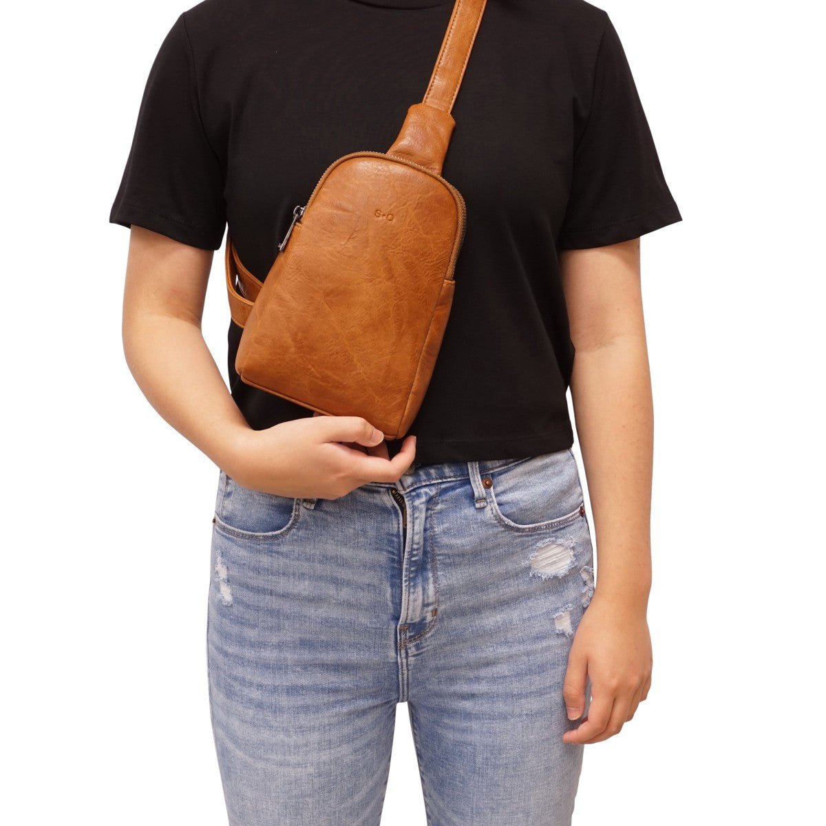Person wearing a brown leather sling bag over one shoulder on a white background - okotoks hc pharmacy