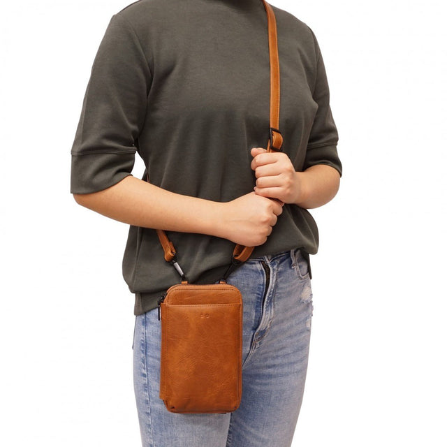 Person wearing a brown leather crossbody bag on a white background - okotoks hc pharmacy
