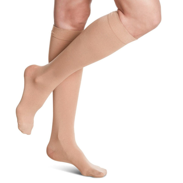 Beige compression stockings being worn on a white background - okotoks hc pharmacy