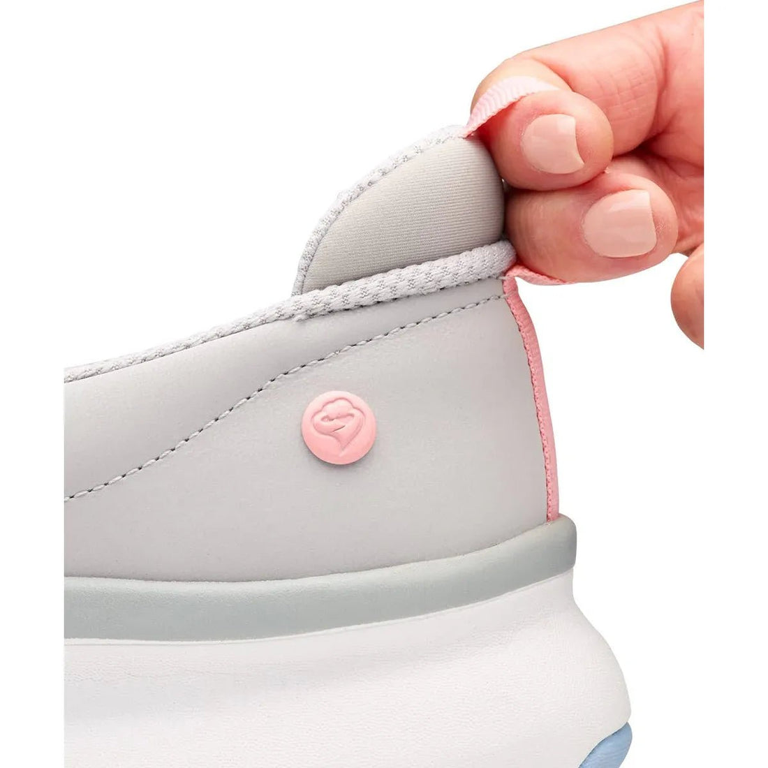 Close-up of a light gray sneaker with pink accents held by a hand. - okotoks hc pharmacy