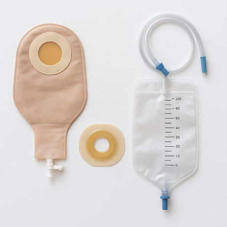 Flat lay of urostomy supplies including a beige drainable pouch with tap, a clear night drainage bag with tubing, and a skin barrier flange on a white background.