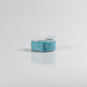 A small turquoise plastic accessory, possibly a strap or clip, sealed in clear plastic packaging and photographed on a light gray background. - okotoks hc pharmacy