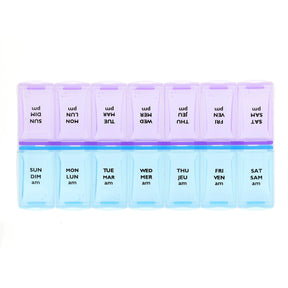 A 7-day weekly pill organizer with translucent plastic compartments. The top row is light purple with black text showing reversed days of the week (SUN, MON, etc. - okotoks hc pharmacy