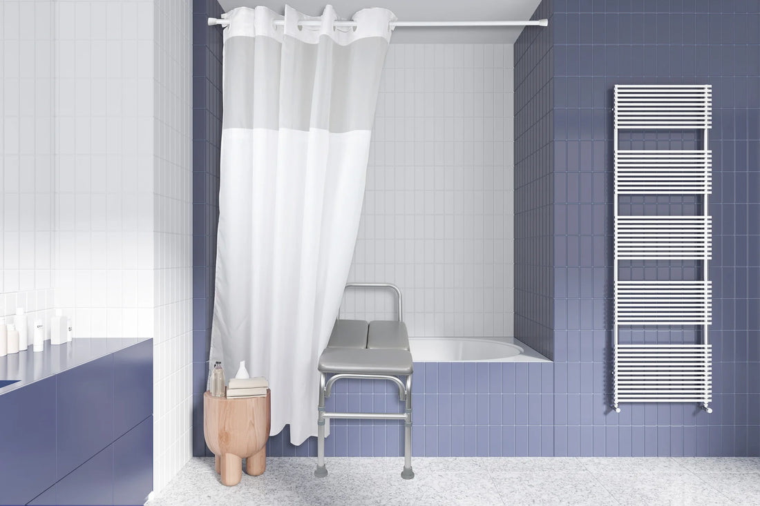A modern bathroom interior with blue tiled walls, a white shower curtain, a bathtub, a metal examination-style stool, and a white heated towel rail. - okotoks hc pharmacy
