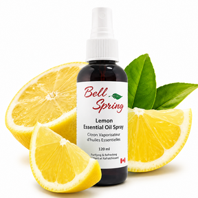 A bottle of Bell Spring Lemon Essential Oil Spray surrounded by fresh lemon slices and green leaves on a white background. - okotoks hc pharmacy