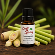 A 15 ml amber glass bottle of Bell Spring Lemongrass Citronnelle essential oil, styled with fresh lemongrass stalks on a rustic wooden surface with a dark, blurred natural background. - okotoks hc pharmacy