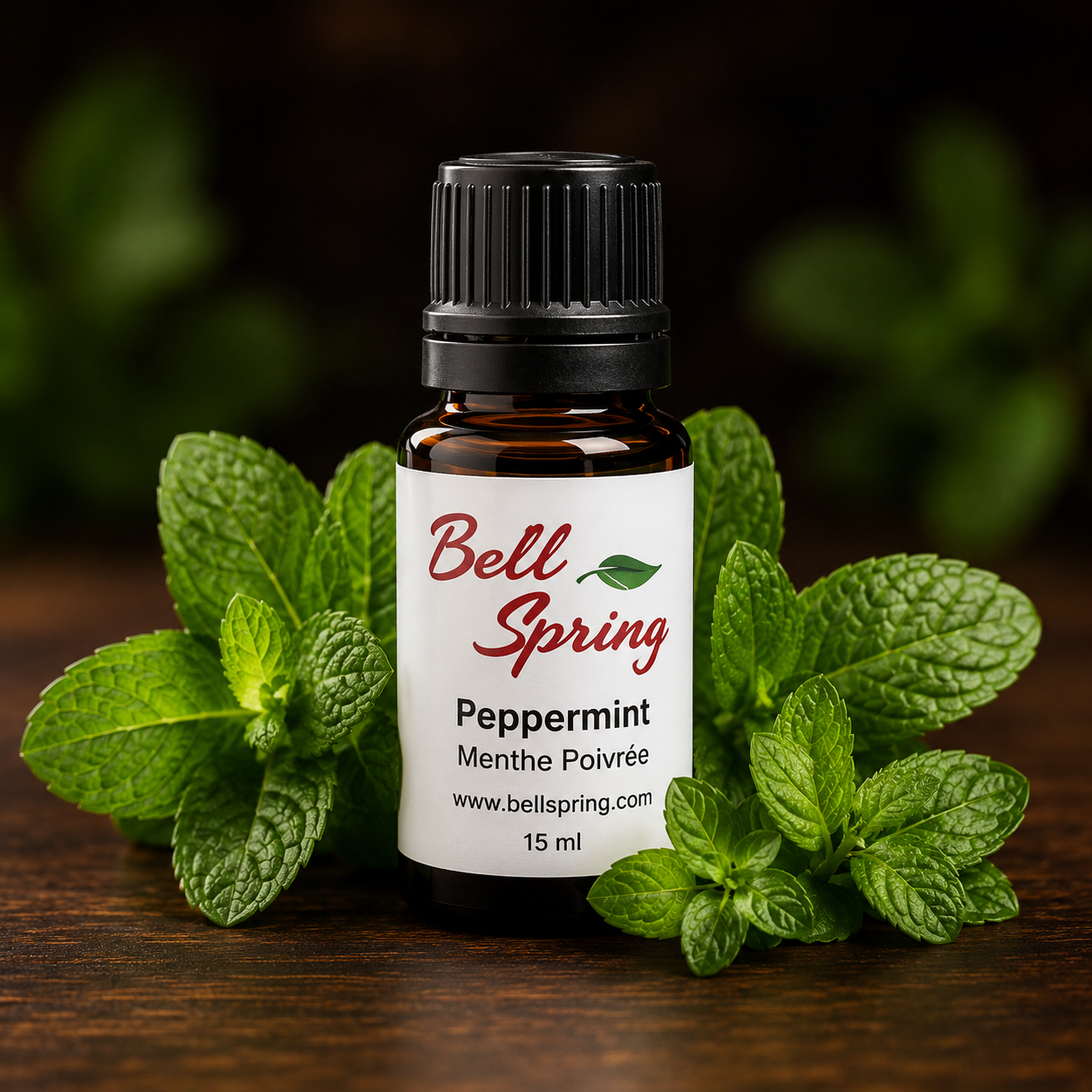A 15 ml bottle of Bell Spring Peppermint Menthe Poivrée essential oil, styled with fresh green peppermint leaves on a dark wooden surface against a dark, blurred background. - okotoks hc pharmacy