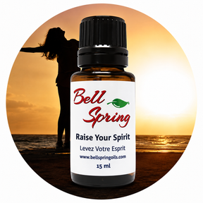 A 15 ml amber glass essential oil bottle with a black cap and a white label reading 'Bell Spring' and 'Raise Your Spirit', centered over a circular beach sunset background with a silhouetted person. - okotoks hc pharmacy