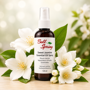 Bell Spring Sweet Jasmine Essential Oil Spray in a dark amber bottle with a white spray top and white label, surrounded by white jasmine flowers and green leaves on a light wooden surface with a soft blurred background. - okotoks hc pharmacy