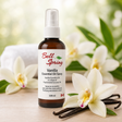 Bell Spring Vanilla Essential Oil Spray in a 120 ml amber glass bottle with a white spray cap, styled on a wooden surface with white orchids and vanilla beans. - okotoks hc pharmacy