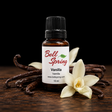 A 15 ml amber glass bottle of Bell Spring Vanilla essential oil with a white label and black cap, styled on a dark wooden surface with vanilla beans and white vanilla flowers against a black background. - okotoks hc pharmacy