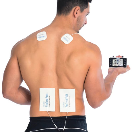 A shirtless man shown from the back on a white background, wearing four square adhesive TENS unit electrode pads on his upper back and lower back while holding a small black electronic controller in his hand. - okotoks hc pharmacy