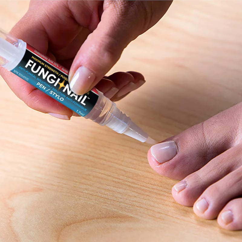 Person applying FungiNail treatment to a toe on a wooden surface - okotoks hc pharmacy