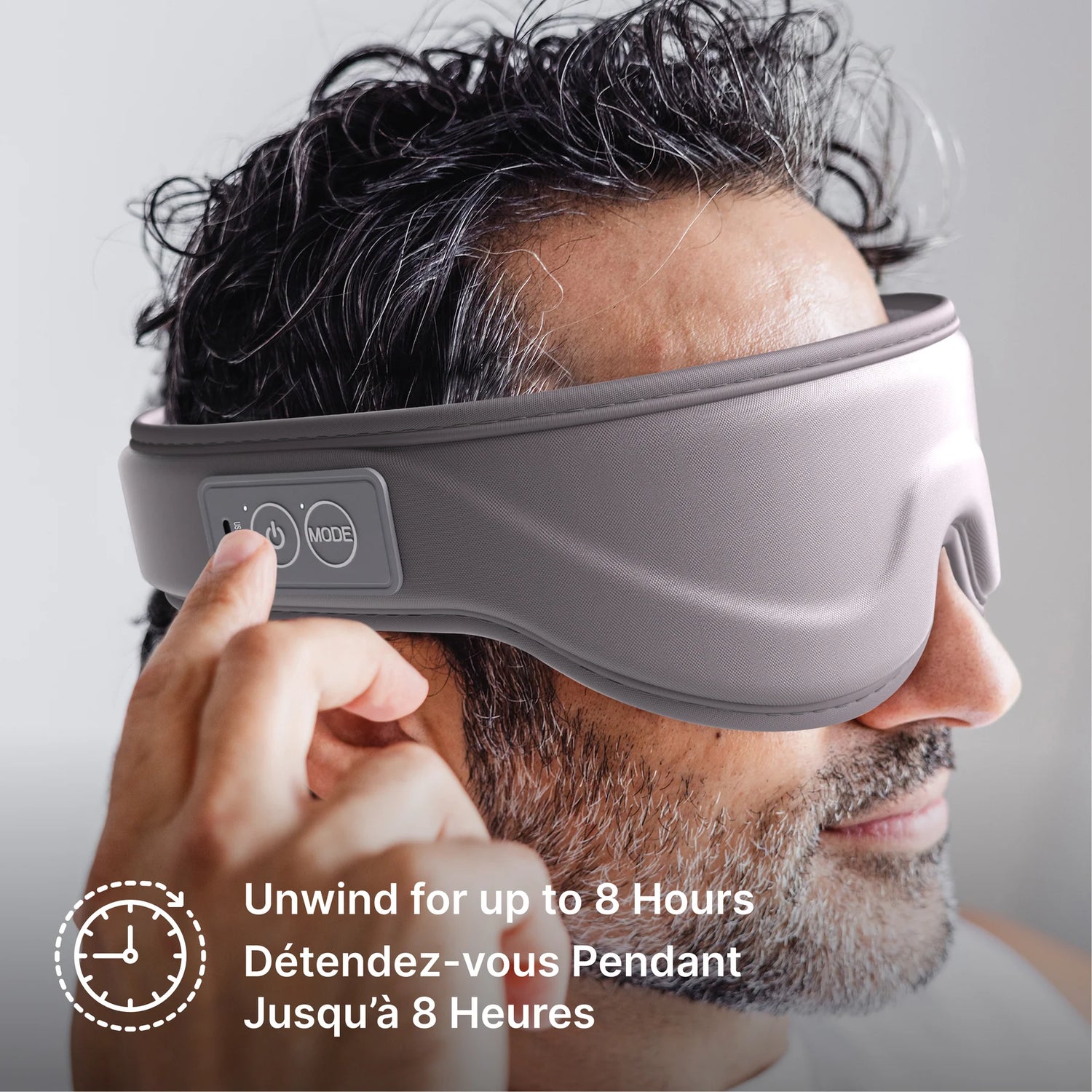 A man wearing a gray electronic eye mask with a control panel on the headband, shown in a close-up profile. French text at the bottom reads 'Unwind for up to 8 Hours'. - okotoks hc pharmacy