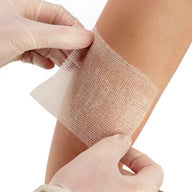 Person applying a bandage to a wound on their arm with gloves on. - okotoks hc pharmacy