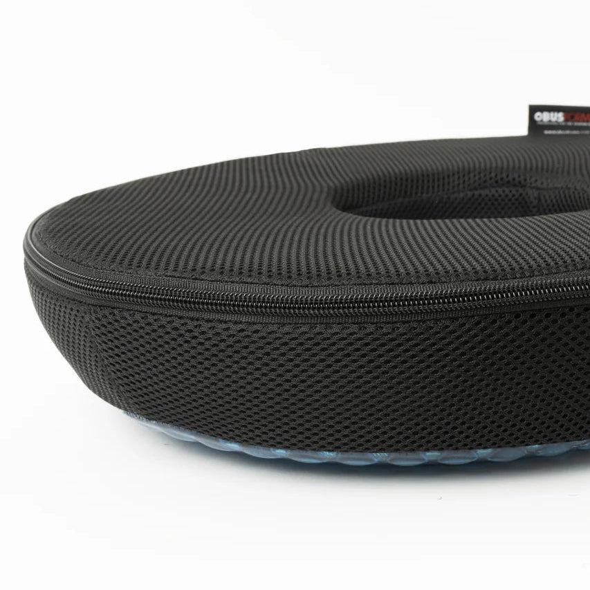 A black textured zippered hard case with a circular opening, shown on a clean white background. A small black brand tag is visible on the upper right edge. - okotoks hc pharmacy