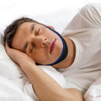 A man sleeping peacefully in bed wearing a blue and black chin strap device. - okotoks hc pharmacy