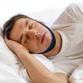 A man sleeping peacefully in bed wearing a blue and black chin strap device. - okotoks hc pharmacy