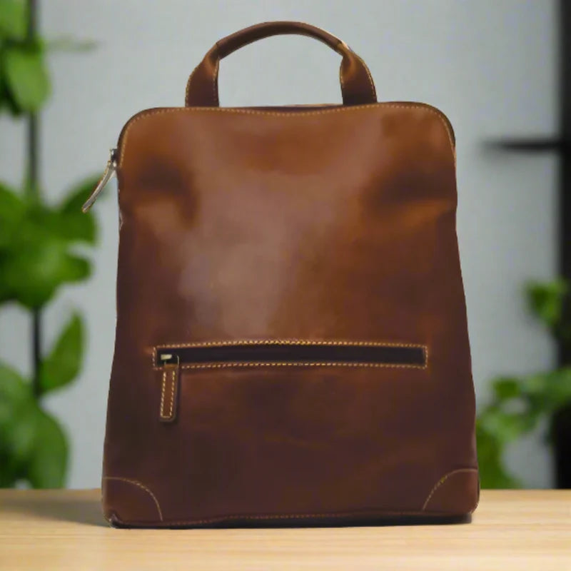 Brown leather backpack on a wooden surface with a blurred green plant background - okotoks hc pharmacy