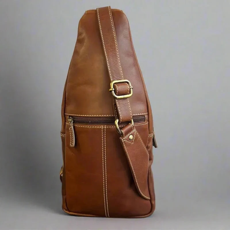 Brown leather sling bag with gold buckle on a gray background - okotoks hc pharmacy