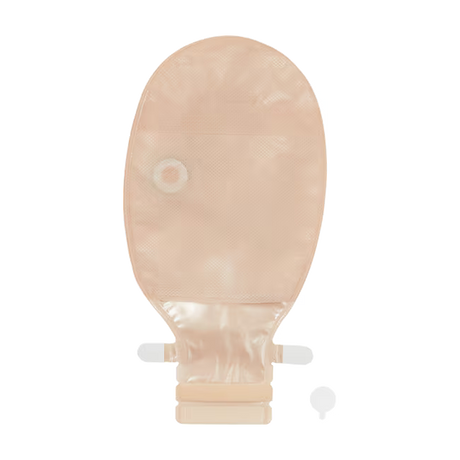 A beige skin-tone disposable abdominal ostomy bag with a central drain hole and a short connector tube, shown on a plain white background with a small matching accessory piece at the bottom right. - okotoks hc pharmacy