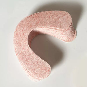 A stack of light pink dental impression trays made of textured paper, photographed on a plain white background with a soft shadow. - okotoks hc pharmacy