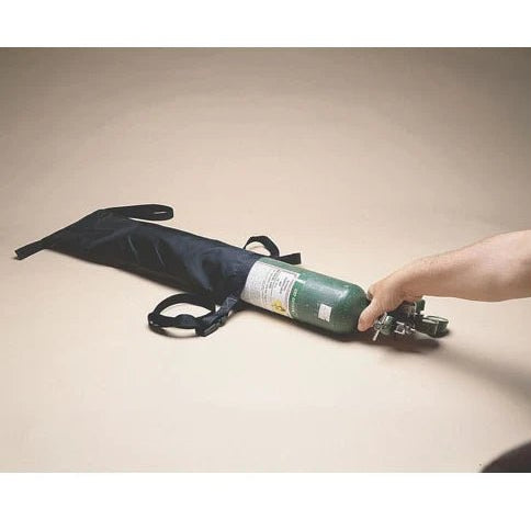 Hand holding a green oxygen tank with black carrying strap on a beige background - Okotoks HC Pharmacy