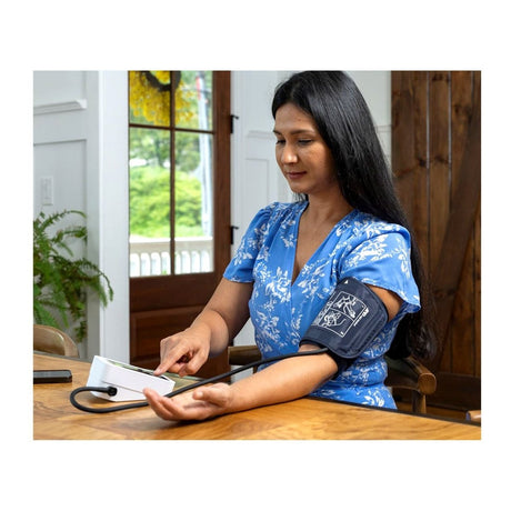 Woman taking her blood pressure at home with a device. - Okotoks HC Pharmacy